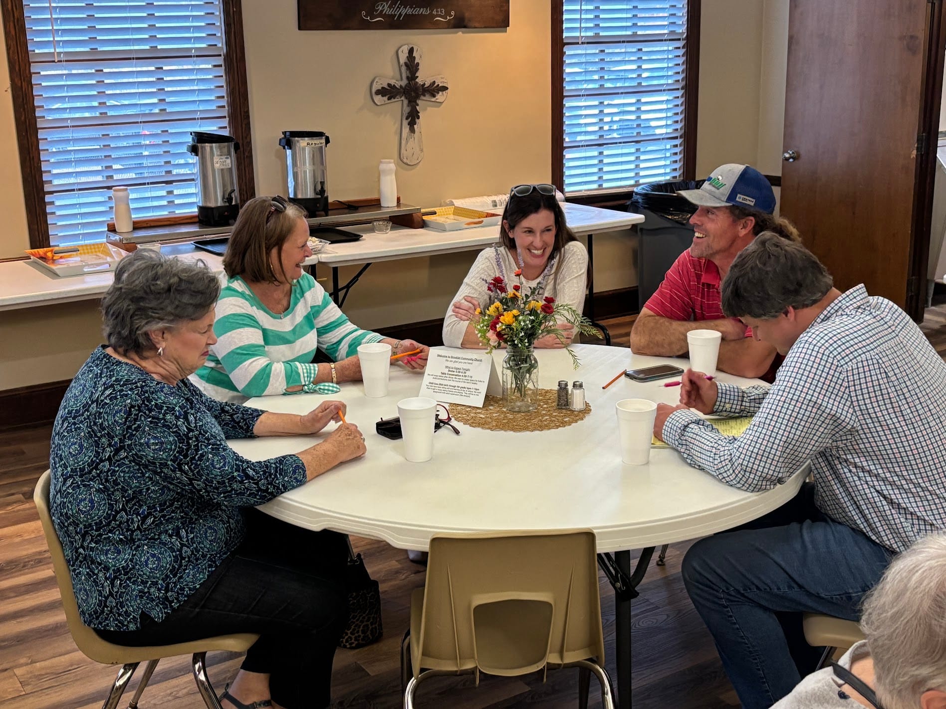 people sitting on chair in front of table while holding pens during daytime